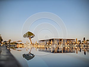 Swimming pool in luxury resort or hotel with view of coconut tree and beach under blue sky