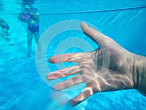 Swimming pool and man`s hand in water