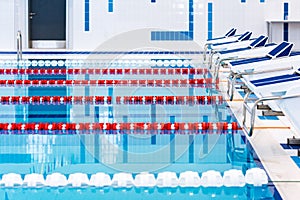 Swimming pool with marked red and white lanes. Empty swimming pool without people with quiet standing water.