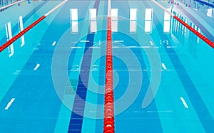 Swimming pool with marked red and white lanes. Empty swimming pool without people with quiet standing water.