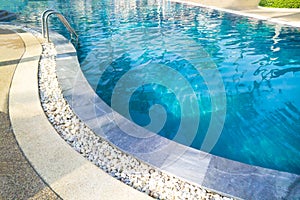 Swimming pool with metal ladder.Fragment of kidney-shaped swimming pool with stair. Cleaning blue color water