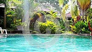 Swimming pool and palm trees in tropical garden with bamboo bungalow. paradise for tourists on sunny day with lens flare