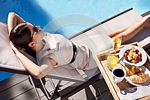 Swimming pool, relax and woman with breakfast, vacation and summer with weekend break and holiday. Person, sunshine and