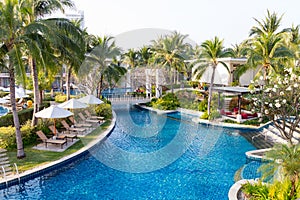 Swimming pool in residential garden with waterfall and chairs