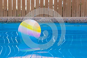 Swimming pool side float ball on water surface soft focus picture and wooden deck wall background view relaxation space for copy