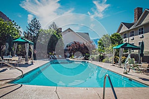 Swimming pool  on sunney day for aprtments or hotel with cabanas around the side and mountains in the distance behind builings photo