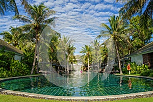 Swimming pool surround with coconut tree and bangalows at seaside resort