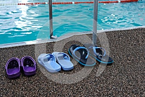 Swimming pool. Three pairs of rubber slippers standing next to each other - men`s, women`s and children`s. Family subscription