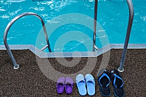 Swimming pool. Three pairs of rubber slippers standing next to each other - men`s, women`s and children`s. Family subscription