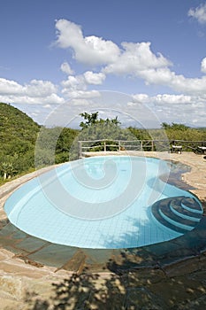 Swimming pool with turquoise water surrounded by the hills of North Kenya, Africa at the Lewa Wildlife Conservancy