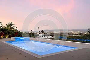 Swimming pool under pink skies and clouds on a sunny day in Encino, California
