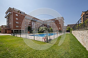 Swimming pool of an urbanization with metal stairs and gardens with grass and stone wall with metal fence