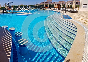 Swimming pool with volleyball net and beach lounges