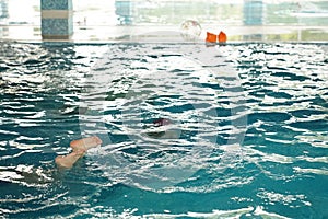 Swimming pool in the water park where children swim. Clear blue water with children& x27;s feet on the background of the