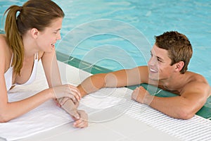 Swimming pool - young loving couple hold hands