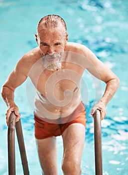 Swimming is super slimming. a happy senior man exercising in a swimming pool at a gym.