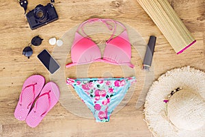 Swimsuit with beach accessories on wood background.