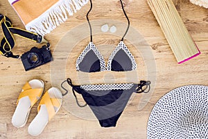 Swimsuit with beach accessories on wood background.