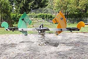 Swing-balancer on springs in the form of horses on a green playground. Empty playground, Green area for games