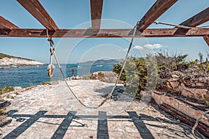 Swing on Bisevo blue cave island near Komiza in Croatia Adriatic sea in summer time