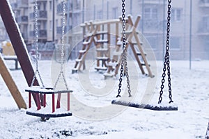 Swing for children in winter. playground near the house