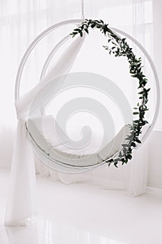 Swing decorated with flowers. White background. White wooden swing in the studio. Wedding decorations