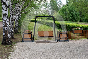 swing and flower beds in garden, place of rest in park