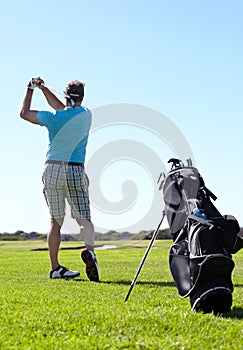 Swing, golf and behind man with driver on a field for training, hobby and sports on blue sky background. Club, swinging