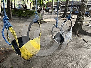 A swing hanging on the tree in the park for leisure activities.