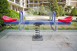 Swing on a metal spiral.Double seats rocking spring . New modern plastic bright colorful blue and red empty toy seesaw swing on