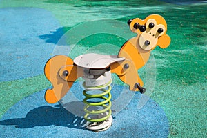 Swing on a a playground with a yellow metal spring in the form of a monkey on rubberized surface. Kids sports