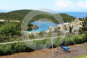 Swing and a view of the blue bay with green mountains and yachts