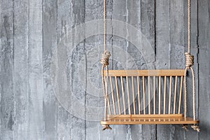 Swing wooden chair on old concrete wall texture