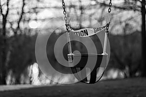 A swing wrapped in caution tape from a shut down park.