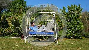 Swinging caucasian man sleeping on hammock at garden, swing