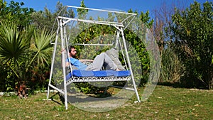 Swinging caucasian man sleeping on hammock at garden, swing