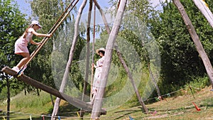 swinging. Happy two girls are having fun swinging together on a big wooden swing, in the park, sunny summer day. Happy