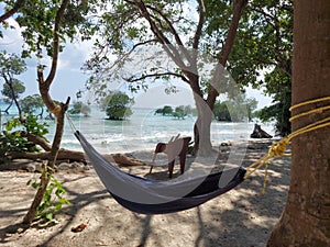 Swings hang from trees for tourists  at neil islands of andaman and a chair with a background of the indian ocean