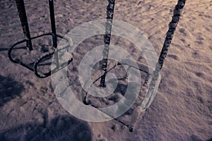 Swings on playground covered with fresh snow