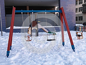 Swings in a playground covered by snow