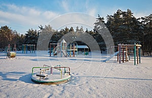 Swings at the playground covered with snow in winter time.