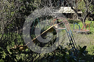 Swings and slides in abandoned overgrown playground