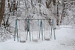 Swings in a snow covered children`s playground