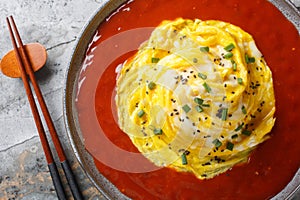 Swirl omelette tornado with fried rice and hot pepper sauce close-up in a plate. Horizontal top view