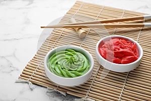 Swirl of wasabi paste, pickled ginger, chopsticks and bamboo mat on white marble table