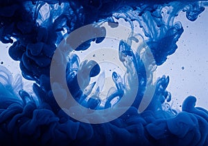 Swirling blue ink clouds through clear