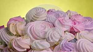 Swirls of sweet meringue rotating on yellow background. Sweet meringue yellow, pink and purple color in confectionery