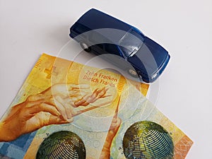 swiss banknotes and figure of a car in dark blue