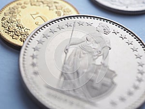 Swiss coins lie on light blue surface. 1 one frank coin close up. Illustration about economy, business or banking. Money and