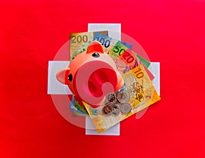 Swiss currency, Swiss franc.Photo of a piggy bank on top of a wad of swiss bills on a swiss flag